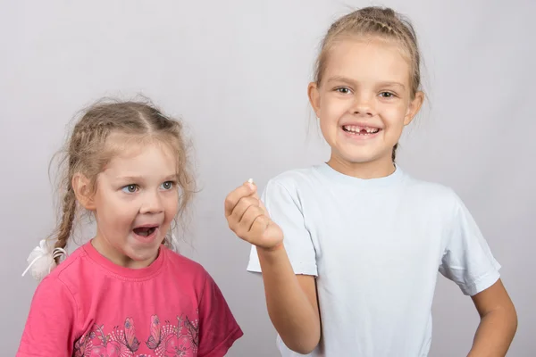 Menina de quatro anos com olhar surpresa para o dente perdido em sua mão uma menina de seis anos — Fotografia de Stock