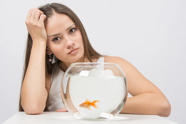 Upset young girl sitting next to the fishbowl — Stock Photo, Image