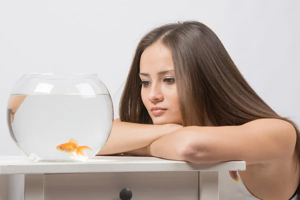 Triste giovane ragazza guardando con indifferenza il piccolo pesce rosso — Foto Stock