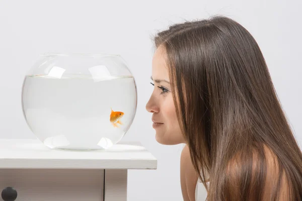 Menina jovem inclinado rosto para o aquário e olhando para peixinho dourado — Fotografia de Stock