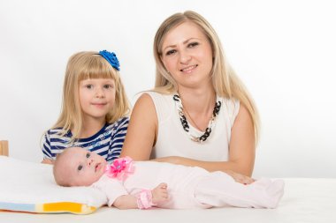 Five-year girl, mother and newborn baby are looking into the frame