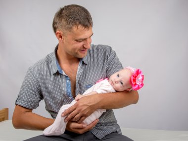 Joyful father holding newborn daughter and looks at her