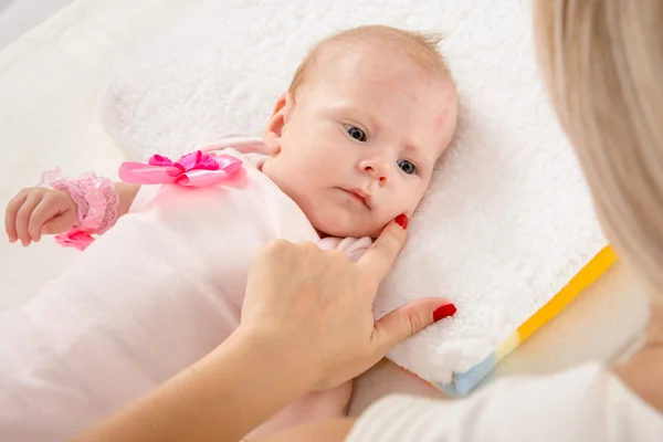 Mom leaned her finger to her cheek two-month girl — Stock Photo, Image