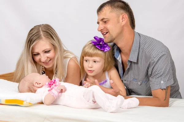 Mãe, pai e filha estão considerando um bebê recém-nascido de cinco anos — Fotografia de Stock