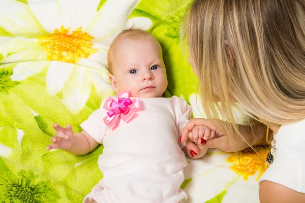 De twee maanden durende baby liggend op het bed, zitten naast de moeder — Stockfoto