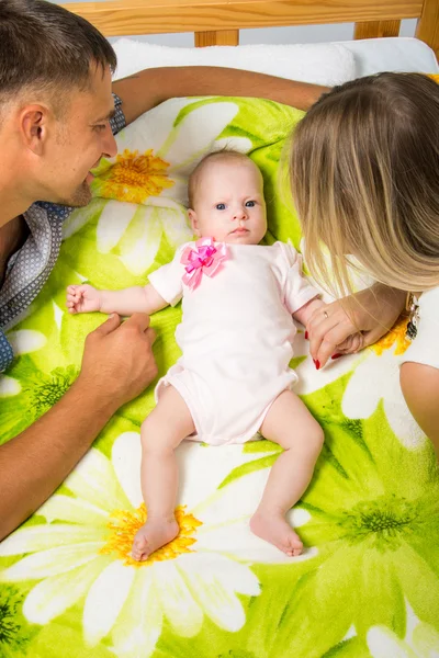 Maman et papa sont assis autour d'un bébé de deux mois qui est couché sur le lit — Photo