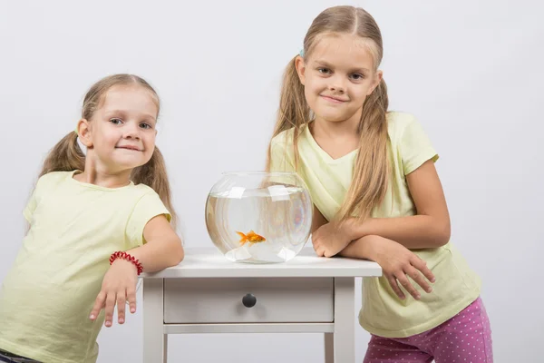 Dwie siostry stoją małe akwarium ze złotą rybką — Zdjęcie stockowe