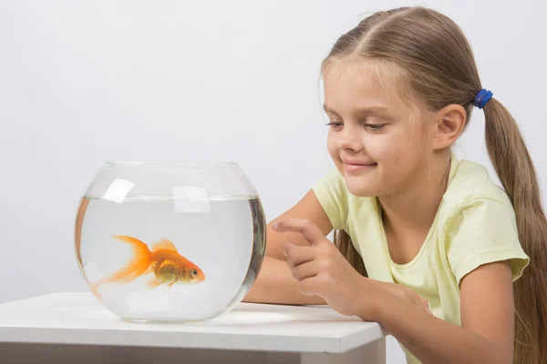 Feliz niña golpeando su dedo en el acuario con peces de colores — Foto de Stock