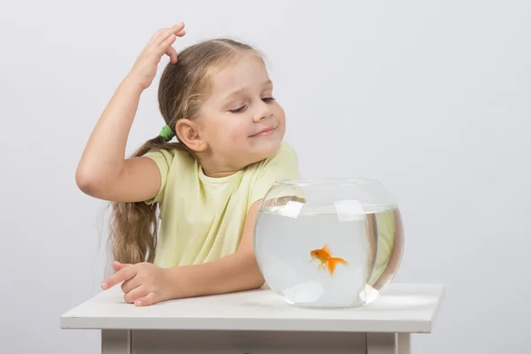 Четырехлетняя девочка загадывает желание, наслаждаясь золотой рыбкой в аквариуме — стоковое фото