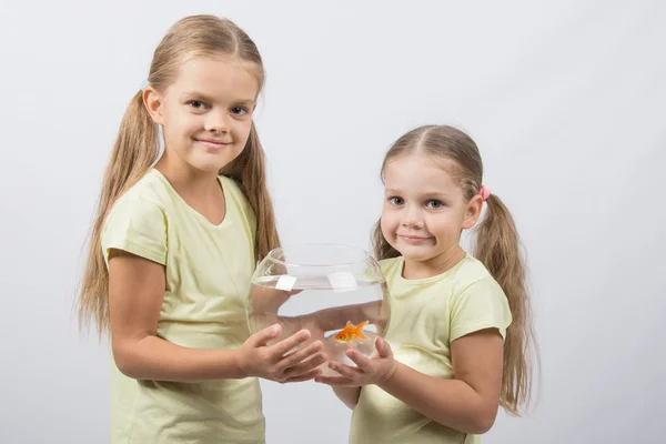 Две девушки держатся за руки в аквариуме с золотыми рыбками — стоковое фото