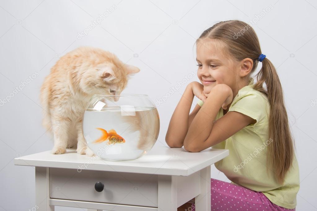 The girl looks like a cat wants to catch the goldfish