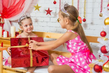 The girl gave a big red Christmas gift to his sister