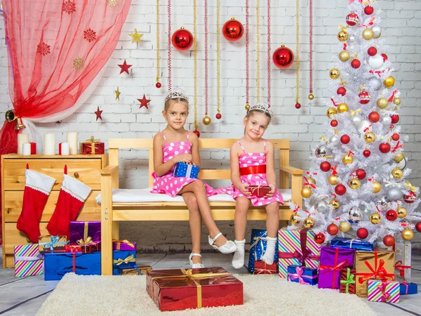 Счастливая сестра с подарками в руках, и сидеть на скамейке в рождественской обстановке — стоковое фото