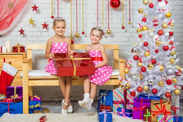 Ragazza felice che ha dato un grande regalo seduto su una panchina in un ambiente di Natale — Foto Stock