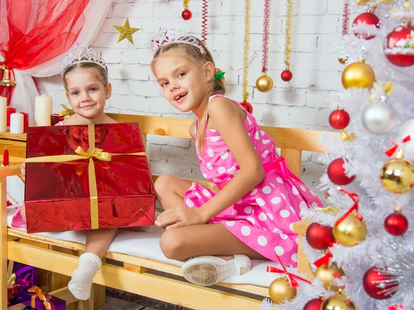 The girl gave a big red Christmas gift to his sister and looked into the frame — Zdjęcie stockowe