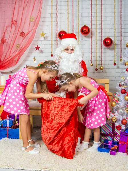 The girls digging in the bag with gifts that brought Santa Claus — Stockfoto