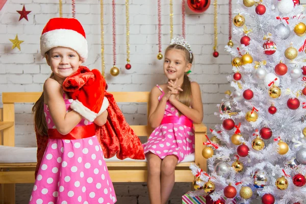 Flicka klädd som jultomte kom med gåvor i påsen den andra flickan — Stockfoto