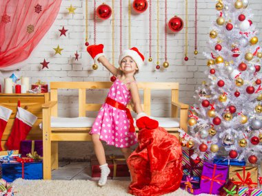 Kız bir kap ve Claus Santa Noel hediyeleri ile çanta etrafında dans eldivenler