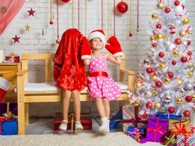 Bir kız bir kap ve Noel Baba'nın mittens bankta oturur, diğer kız kafasına bir torba giydi