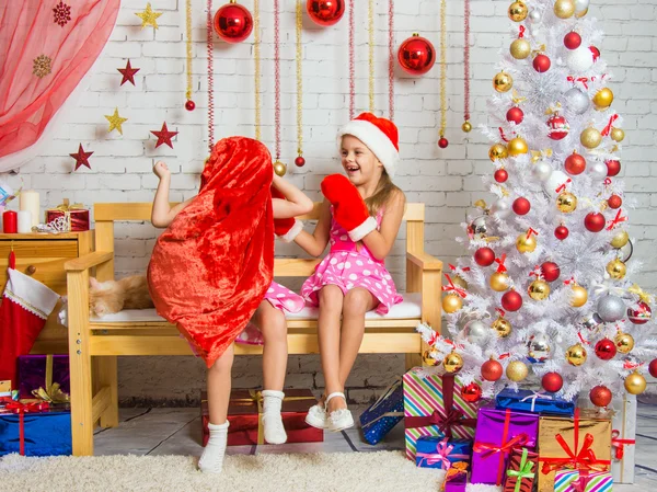 Chica con gorra y manoplas de Santa Claus riéndose de la chica que le puso un saco en la cabeza — Foto de Stock