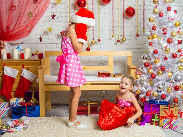 Девушка в кепке и варежках Санта Клауса была очень удивлена, что из сумки вылезла другая девушка — стоковое фото