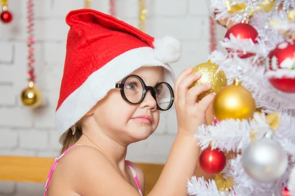 Chica con gafas redondas cuelga bolas en un árbol de Navidad nevado de Año Nuevo — Foto de Stock