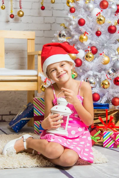 Chica feliz sosteniendo una vela en su mano y sentada en los árboles de Navidad — Foto de Stock