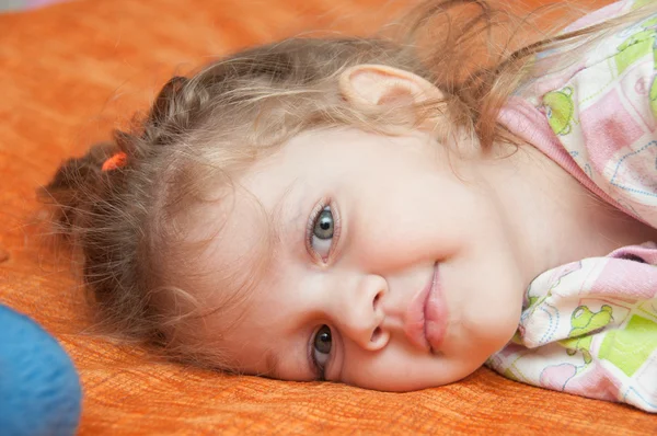 Портрет веселой трехлетней девочки, лежащей на диване — стоковое фото