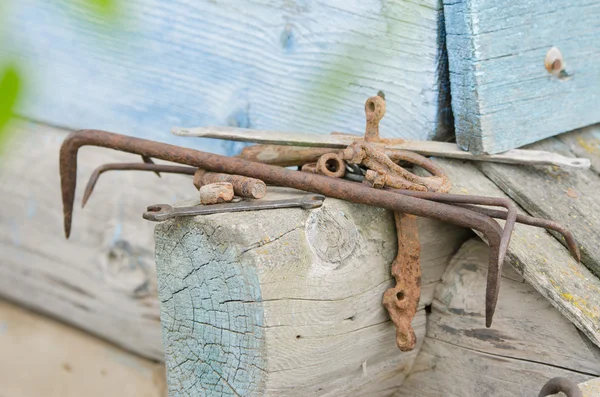 Pilha de ferramentas antigas e pedaços de ferro deitado sobre a moldura de madeira da casa velha — Fotografia de Stock