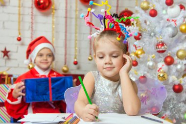 She writes a letter to Santa Claus, who is sitting with a gift behind her