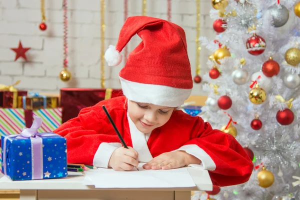 Girl dressed as Santa Claus writing a list of desired gifts for Christmas — Stock fotografie