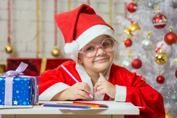 Chica vestida como Santa Claus con gafas y tarjeta de dibujo para Navidad —  Fotos de Stock