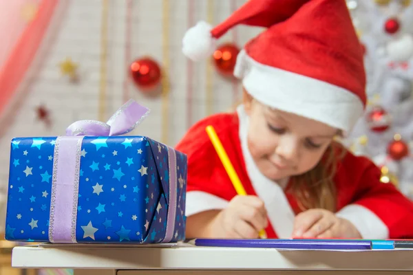 Regalo de Año Nuevo en primer plano, en el fondo Chica dibuja lápiz — Foto de Stock