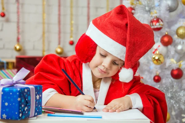 Girl with enthusiasm writes congratulations Christmas card — Stock fotografie