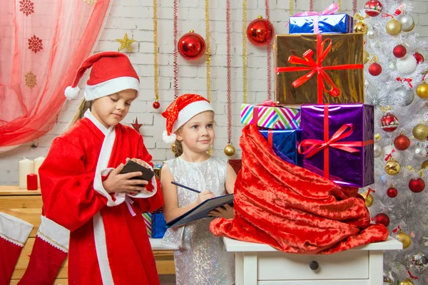 Papai Noel e ajudante verificado saco com presentes — Fotografia de Stock