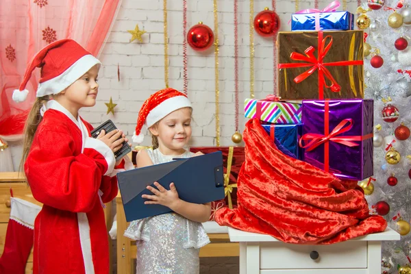 Santa Claus y asistente cuentan regalos en una bolsa — Foto de Stock