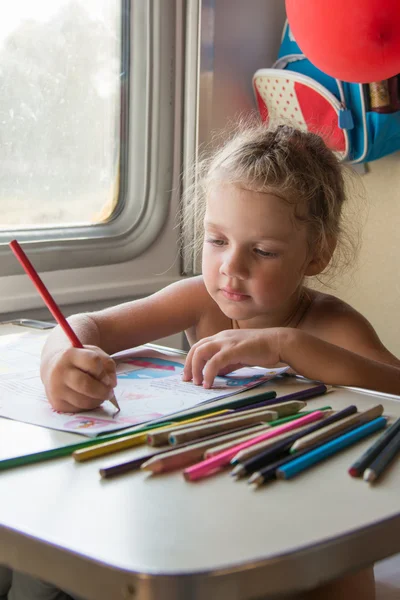 Четырехлетняя девочка рисует карандашами за столом в поезде — стоковое фото