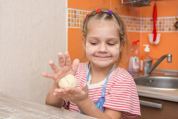 Menina feliz esculpe uma torta na mesa da cozinha — Fotografia de Stock