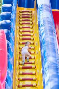 Büyük bir hava ile şişirilen trambolin üzerinde üç yaşındaki kız tırmanıyor