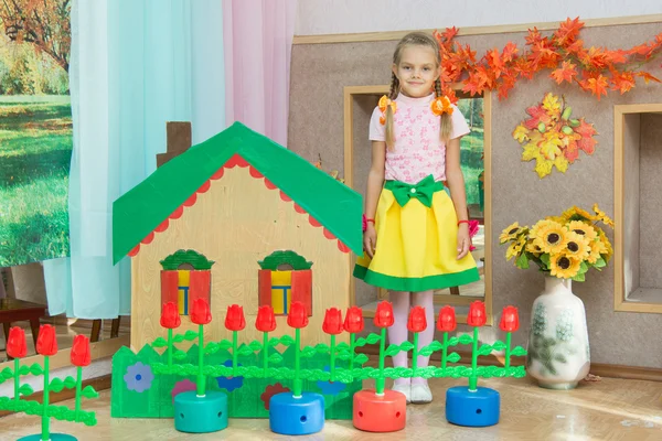 A girl stands at the scenery house on matinee in kindergarten — Stock Photo, Image