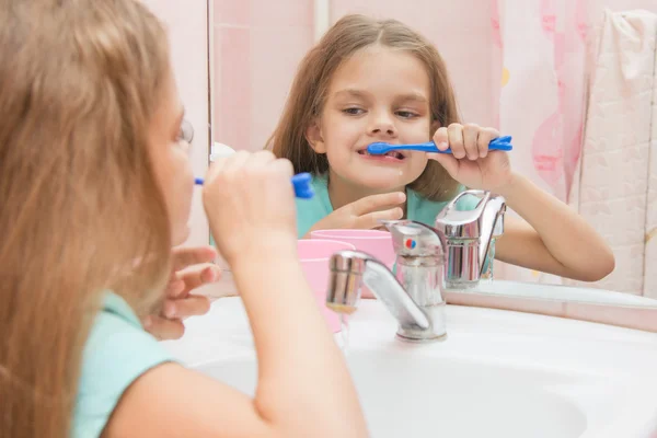 Ragazza di sei anni che si diverte a lavarsi i denti guardarsi allo specchio in bagno — Foto Stock