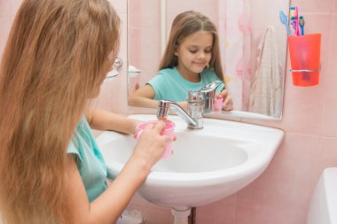 Kız ağzını durulama için sıcak su bir bardak içki alıyor.