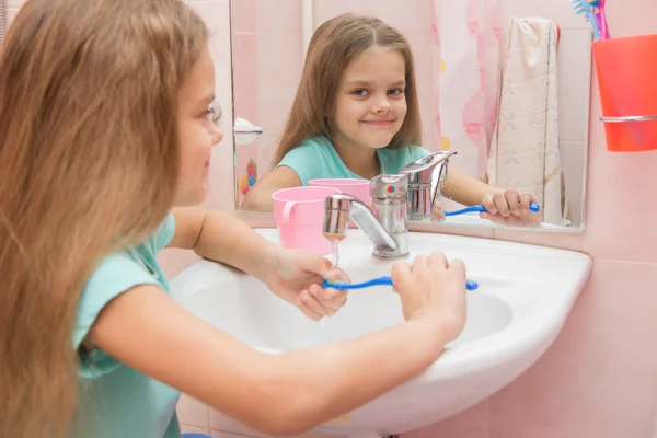 Das Mädchen wäscht eine Zahnbürste unter dem Wasserhahn — Stockfoto