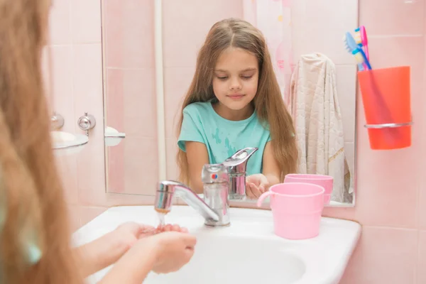 Chica vierte sus manos agua del grifo en el baño —  Fotos de Stock