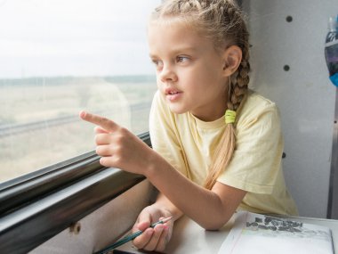 Girl shows a finger in the second-class car of a train window