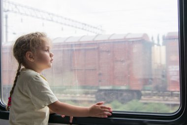 Girl thoughtfully looking into the distance from a train window