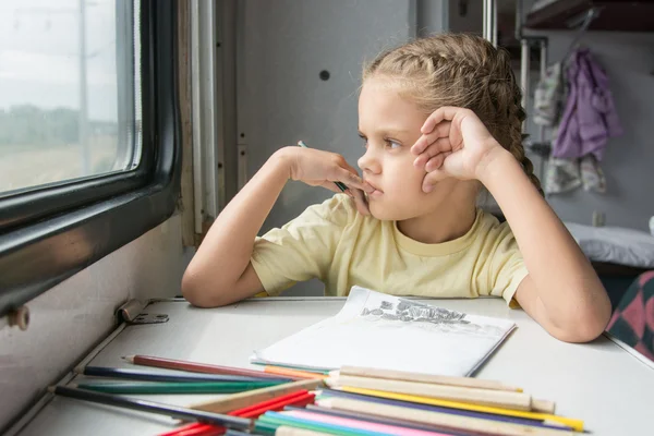 La ragazza guardò fuori dalla finestra pensando matite di disegno in un treno — Foto Stock