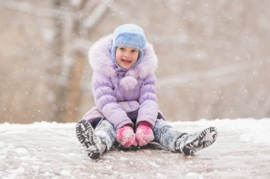 Joyful child slides down the icy hill