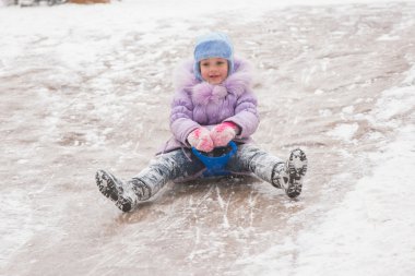 Five-year girl rolls on in the middle of the ice slides