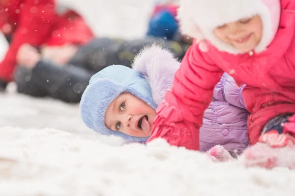 显示舌的女孩从山上滚下来，掉进雪 — 图库照片
